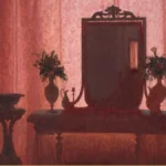 Detail of a nineteenth-century interior: an empty room with a dark mirror on rose patterned wallpaper, flanked by vases of dried flowers.