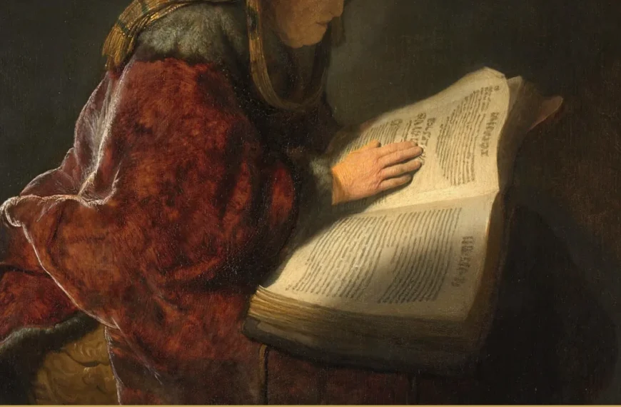 Detail of a Rembrandt painting: a figure in a deep red robe stands at a lectern with one hand resting on a large open printed book.